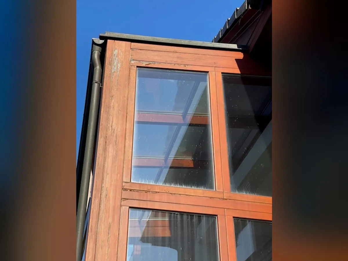Detail zvětralých rámů prosklené stěny před renovací